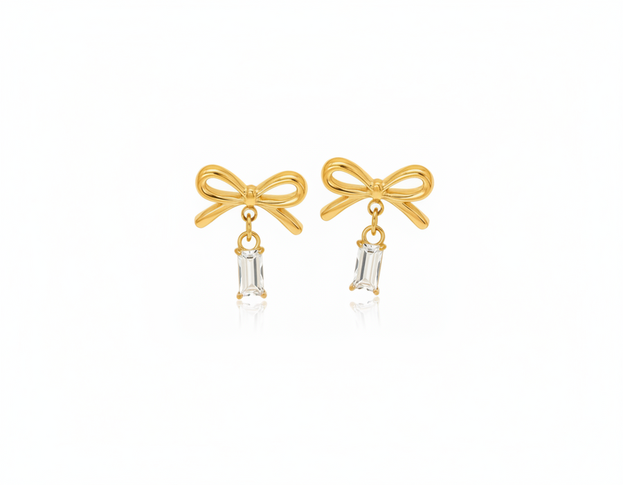 Gold bow-shaped earrings with clear gemstones on a white background